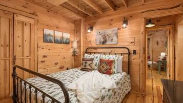 Un dormitorio de cabaña de madera con una cama, una mesita de noche y una lámpara fijada a la pared.