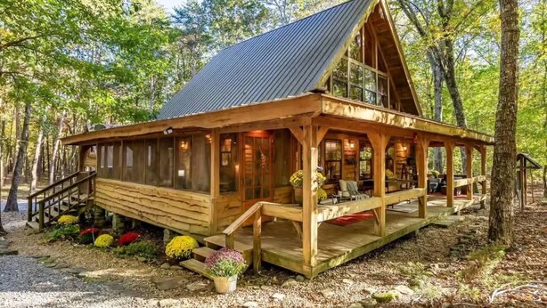 A wooden cabin with a metal roof, a porch, and a staircase leading to the entrance. - Hot Tub, Fire Pit & Games! Family Falcon Lodge (Mentone)