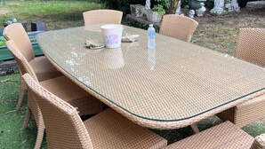Una mesa con cubierta de vidrio y sillas de mimbre trenzado.