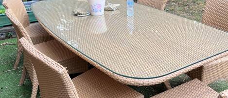 A glass-top table with woven wicker chairs.