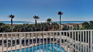 A pool area with a view of the beach and palm trees. - Tidewater (Orange Beach) #108 | Gulf Front + Resort Amenities (Orange Beach)