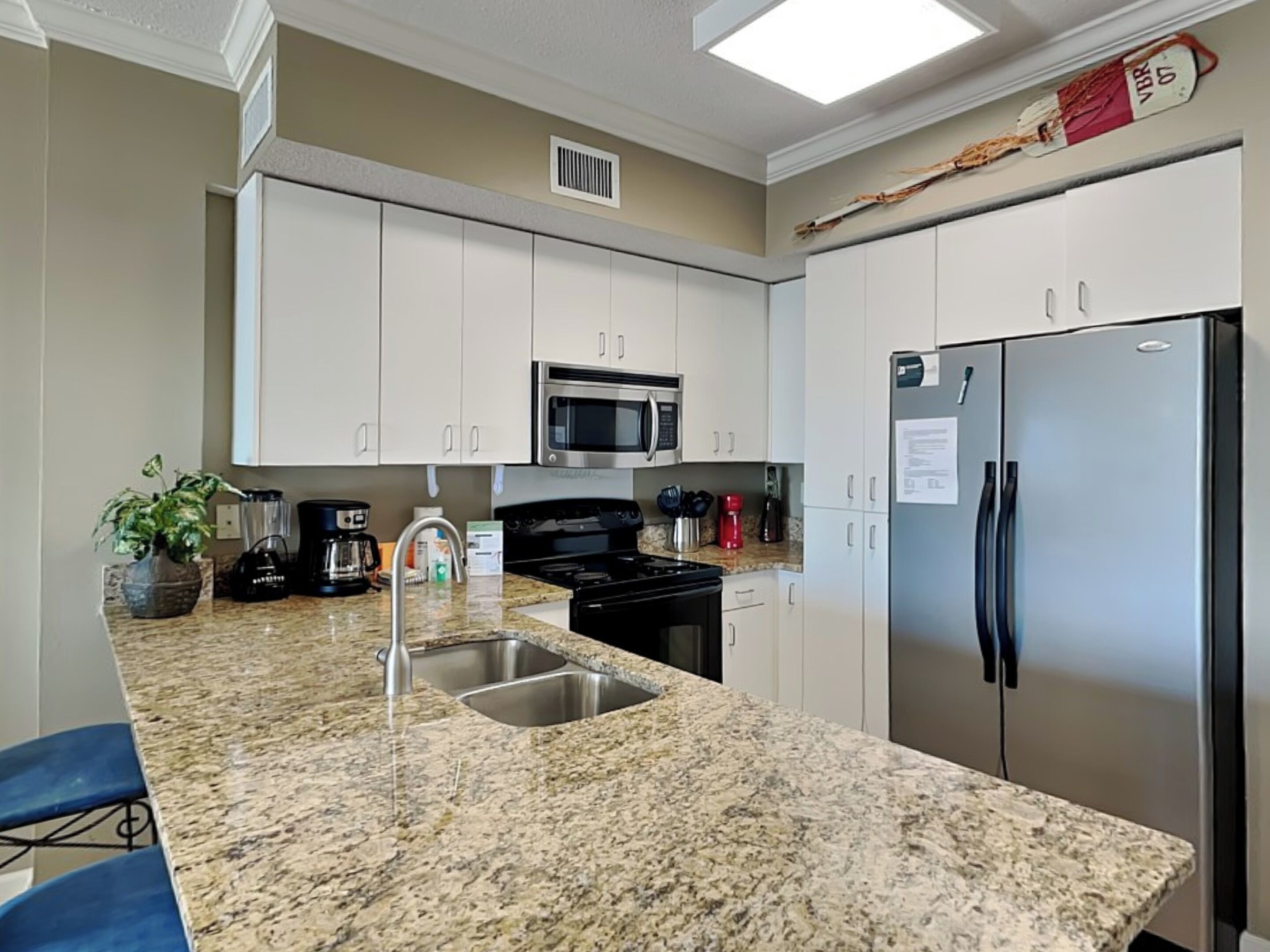 A modern kitchen with granite countertops, stainless steel appliances, and white cabinetry.