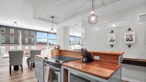 A modern kitchen with a wooden countertop, stainless steel appliances, and pendant lighting.