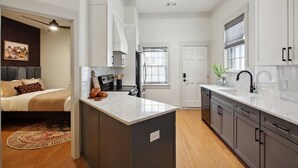 Une cuisine moderne dotée d’un îlot central, de meubles de couleur gris foncé et d’un plan de travail blanc.