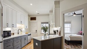 Une cuisine moderne avec des meubles gris, un îlot central et un four à micro-ondes.
