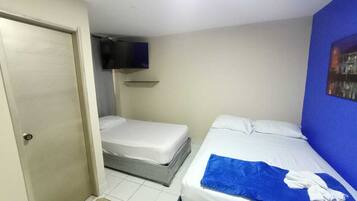 A small, clean room with two beds, a TV, and a door.