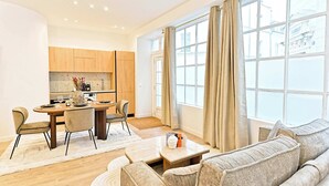 A modern living room with a sofa, a coffee table, and a dining area with a table and chairs. - Sublime air-conditioned flat Galeries Lafayette (Paris)