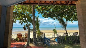 Un espace extérieur abrité, avec vue sur la plage, doté d’un plafond en bois et de murs en briques.