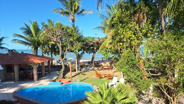 Une piscine entourée de palmiers, avec vue sur la plage.