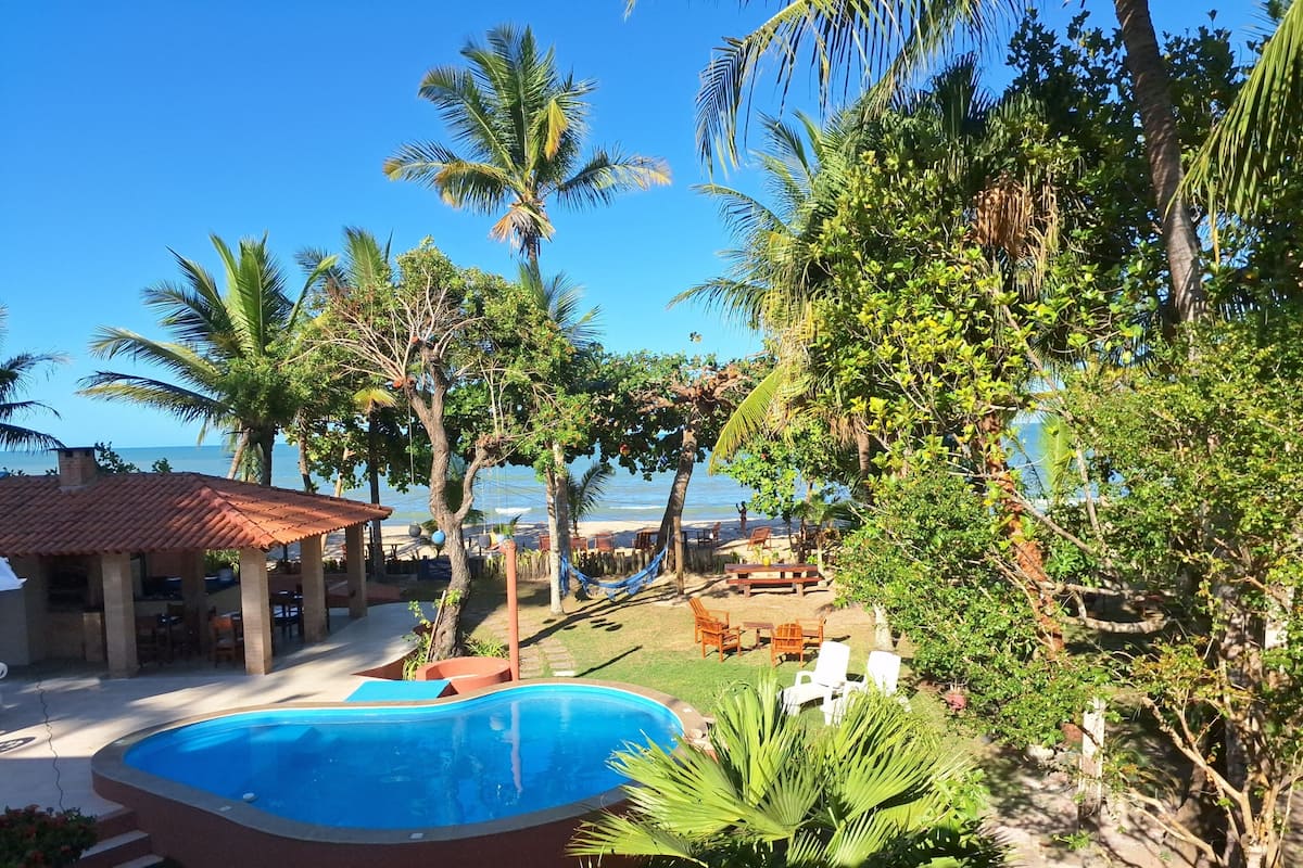 Ein Pool, umgeben von Palmen, mit Blick auf einen Strand.