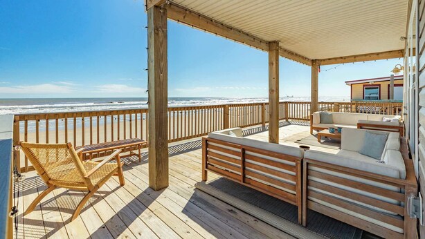 Une terrasse en bois avec un espace salon agrémenté de coussins, offrant une vue sur l’océan.