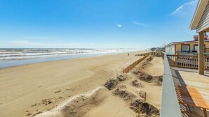 Une vue sur la plage, avec une terrasse en bois et un bâtiment doté d’un balcon.
