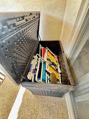 A corner of a room with a textured wall and a metal bin containing various items.