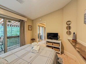 Une chambre d’hôtel avec un lit, une télévision, une petite table et un balcon.