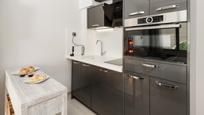 A modern kitchen with dark cabinetry, a white countertop, and stainless steel appliances including an oven and a microwave. - SQUARE Elegant Suite II on Aristotelous Square (Thessaloniki)