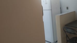 A kitchen with a white refrigerator, a small table, and a chair. - Private pool house (Abrantes)