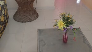 A room with a wicker table, a red mug, a floral sofa, and a vase with flowers. - Private pool house (Abrantes)