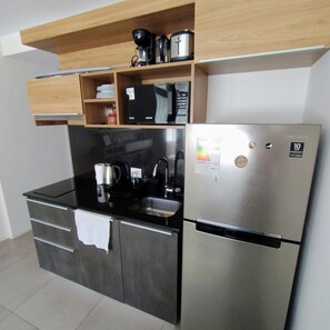 A modern kitchen with a stainless steel refrigerator, a microwave, and a coffee maker on the countertop. - Convenient Studio in Santa Cruz (Santa Cruz de la Sierra)