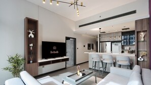 Una sala de estar moderna con televisor de pantalla plana, un sofá, una mesa de centro y una zona de cocina con barra.