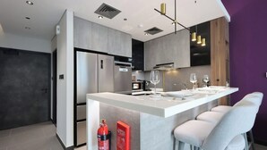 Une cuisine moderne dotée d’un îlot central, d’appareils électroménagers en acier inoxydable et de tabourets de bar.