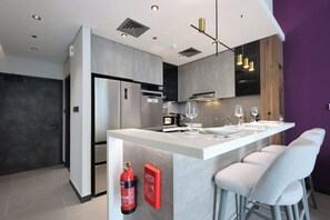 Une cuisine moderne dotée d’un îlot central, d’appareils électroménagers en acier inoxydable et de tabourets de bar.