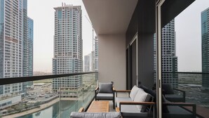 Un balcón con vistas a edificios altos, una mesa de madera y dos sofás.