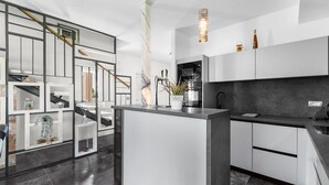 A modern kitchen with a central island, white cabinetry, and a black countertop.