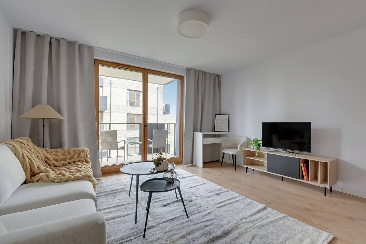 Una sala de estar moderna con sofá, mesa de centro y mueble para televisión.