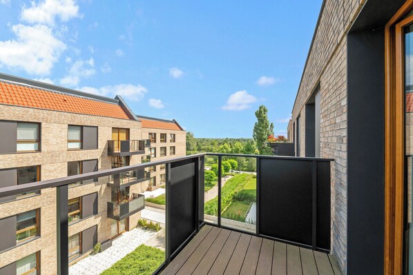 A modern apartment with a balcony overlooking a garden and neighboring buildings. - Lion Apartments - Front Park (Gdansk)