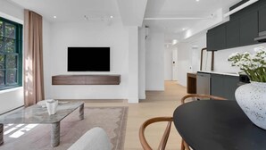 A modern living room with a flat-screen TV, a dining area with a black table, and a kitchen with dark cabinets. - Mercer-King Bedroom -Free parking (Montréal)