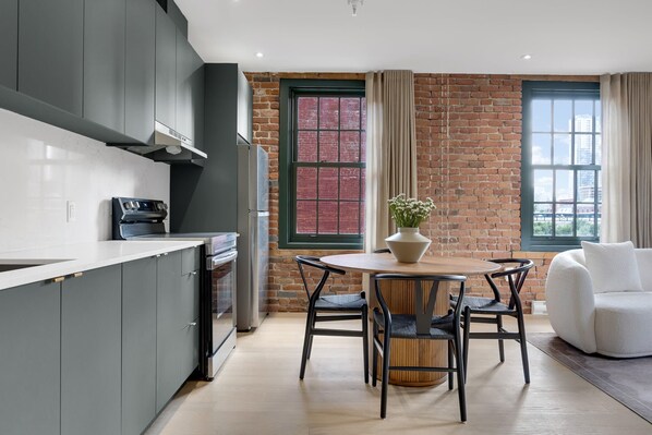 A modern kitchen with grey cabinets, a built-in oven, and a dining area with a round table and chairs.