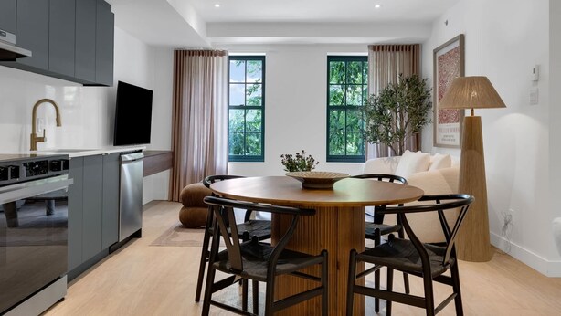 A modern kitchen with grey cabinets, a built-in oven, and a flat-screen TV.
