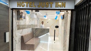 A modern hotel lobby with a marble reception desk, a seating area, and a staircase leading to the upper floors. - Hotel just inn (Ahmedabad)