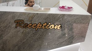 A reception desk with a marble top and the word "Reception" in gold lettering.