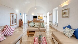 Un salón espacioso con techo alto, un conjunto de sofás, una mesa de centro y un televisor al fondo.