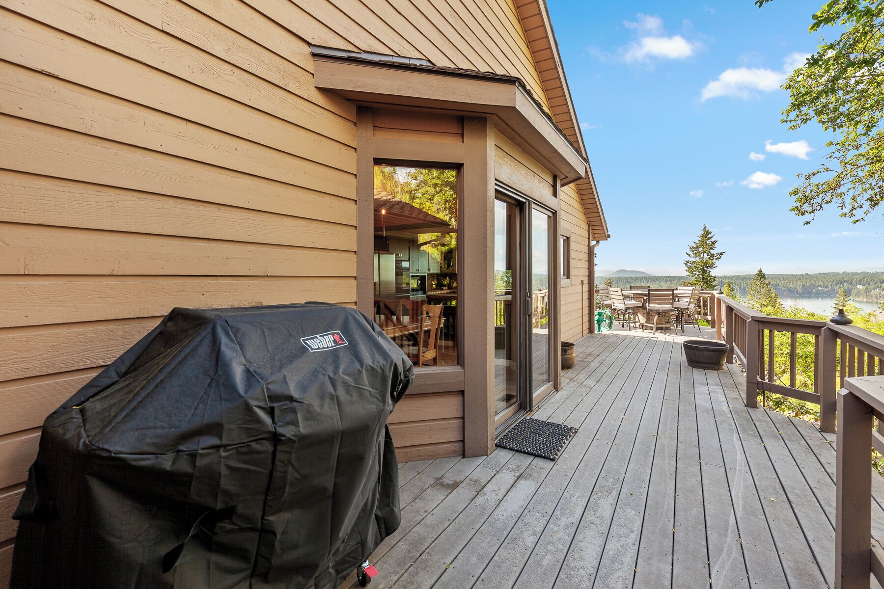 A deck with a grill and a view of a kitchen and dining area.