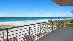 A balcony with a view of the beach and ocean.