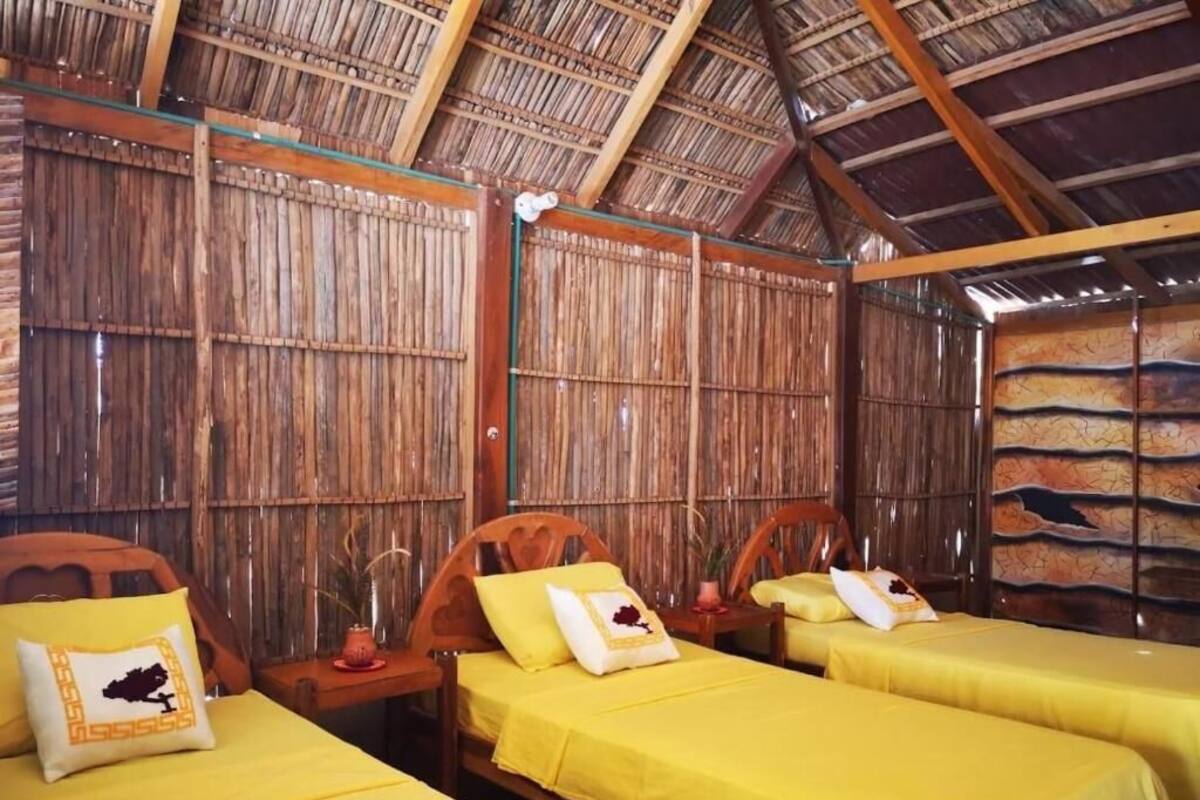 A room with two beds, wooden furniture, and a thatched roof.