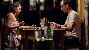 Een eethoek met een tafel gedekt voor twee personen, een waterfles en een glas.