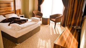 A hotel room with a large bed, two armchairs, a small table, and a bedside telephone. - Tera Life Thermal Hotel (Kozakli)