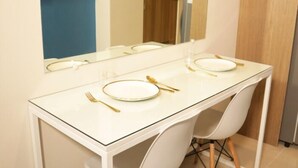 A dining table with white chairs, a mirror above, and a door in the background. - Homefort at S Residences (Pasay)