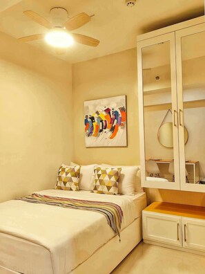 Ein Schlafzimmer mit Bett, Deckenventilator, Gemälde und Kleiderschrank.