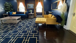 Un soggiorno moderno con una palette di colori blu e giallo, che include un divano, una poltrona gialla, un tavolino da caffè e un tappeto decorato.