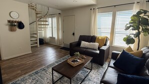 A living room with a sofa, coffee table, and a staircase leading to an upper floor. - Newly Renovated Beachside Complex~2BR/1.5B w/Pool (Gulf Shores)