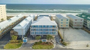 A beachfront hotel with multiple buildings, including a central structure with a sloped roof and a series of smaller buildings with flat roofs. - Beachside Complex/Heated Pool/2BD,1BA (Gulf Shores)