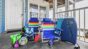 A porch with two beach chairs, a surfboard, a green bucket, and a soccer ball. - Beachside Complex/Heated Pool/2BD,1BA (Gulf Shores)