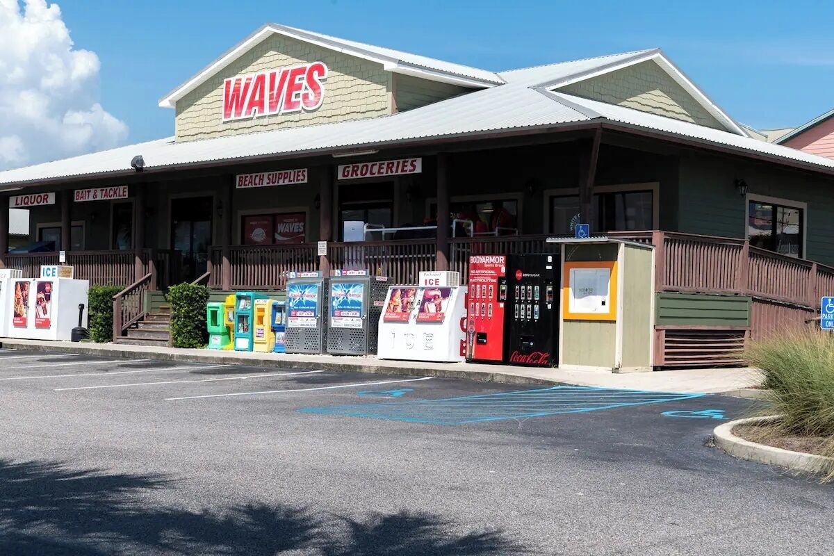 A building with a sign reading "WAVES" and sections labeled "LIQUOR," "BAIT & TACKLE," "BEACH SUPPLIES," and "GROCERIES."