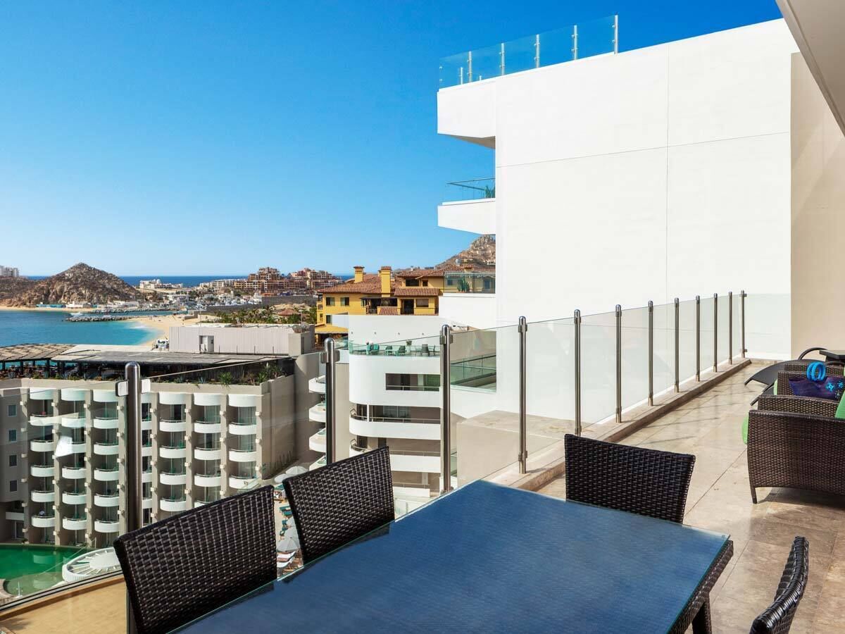 Una terraza en la azotea con piscina, zona de comedor y vistas a la playa y al paisaje urbano.