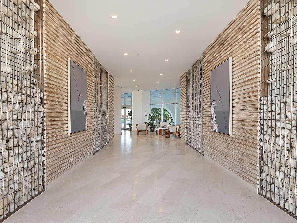A hallway with a tiled floor, wooden panel walls, and framed artwork.