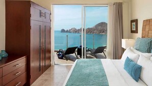 Een hotelkamer met een bed, een kledingkast, een bureau en uitzicht op zee.